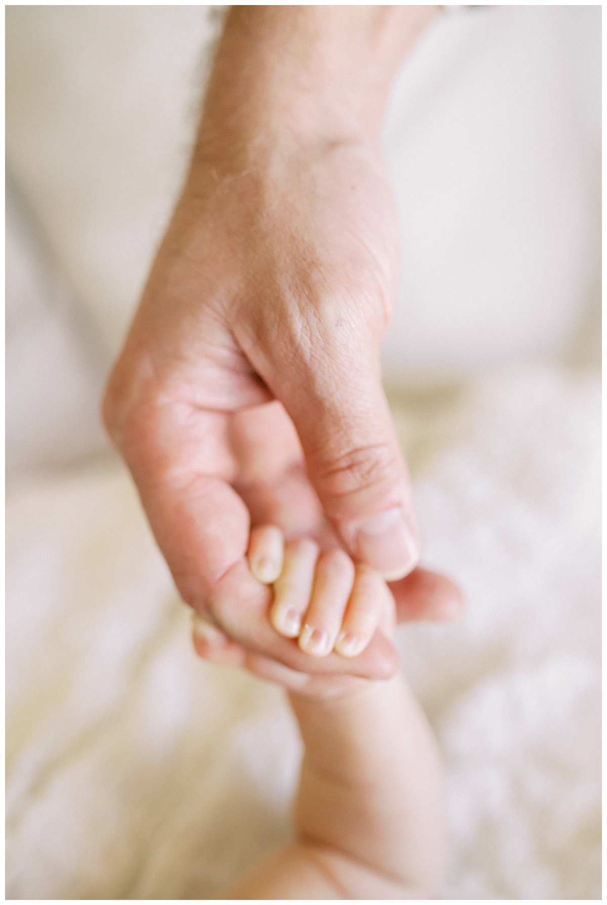 a newborn holding their father's finger